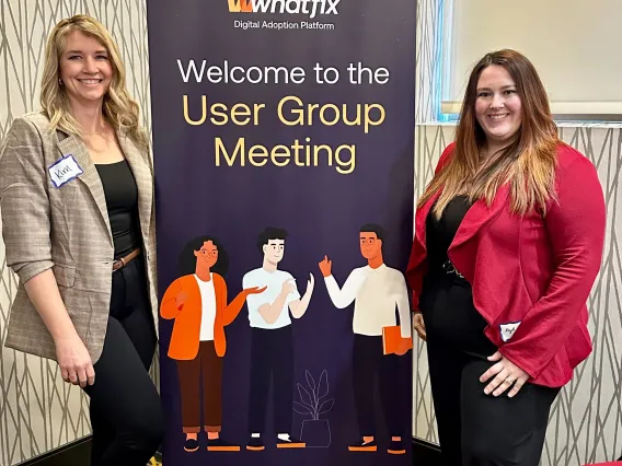 Kim Winchell and Kayli Hill standing beside Whatfix pop-up banner